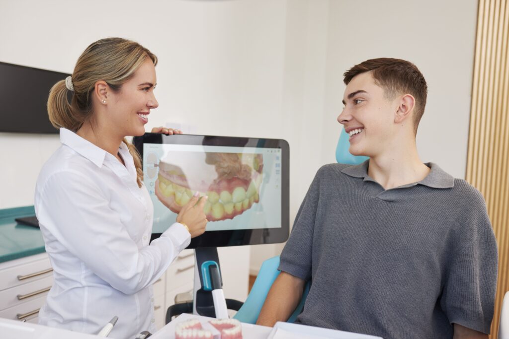 Kieferorthopädin Dr. med. dent. Jennifer Hoppe von der Fachzahnarztpraxis Biss & Bogen in Ratingen-Lintorf erklärt einem jungen Patienten anhand eines digitalen Zahnmodells auf einem Bildschirm den Behandlungsplan.